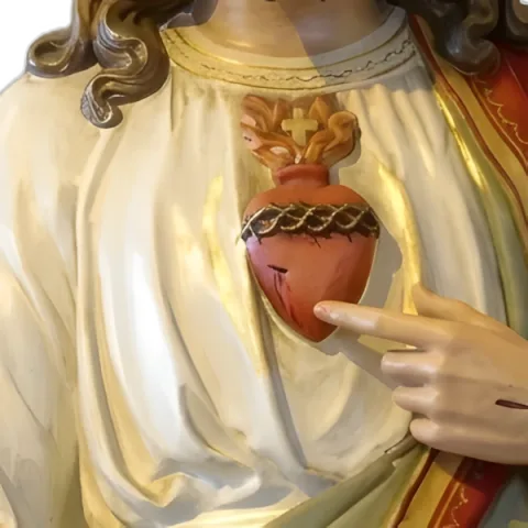 The Sacred Heart aflame, ringed with thorns and topped with a cross, on Christ’s breast: detail of a Simon Art Co. statue